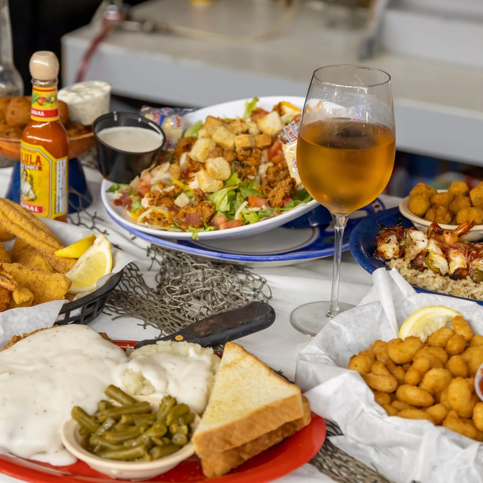 A spread of seafood, salad, shrimp, and chicken fried steak.